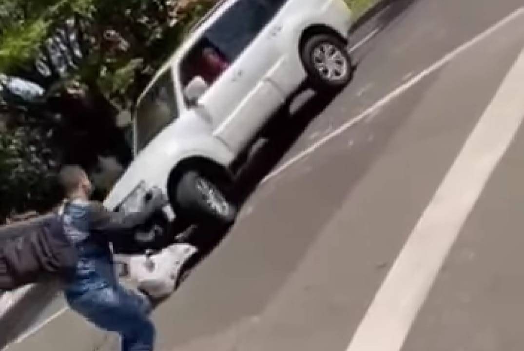 A imagem mostra um motoqueiro tentando escapar de atropelamento no meio da rua