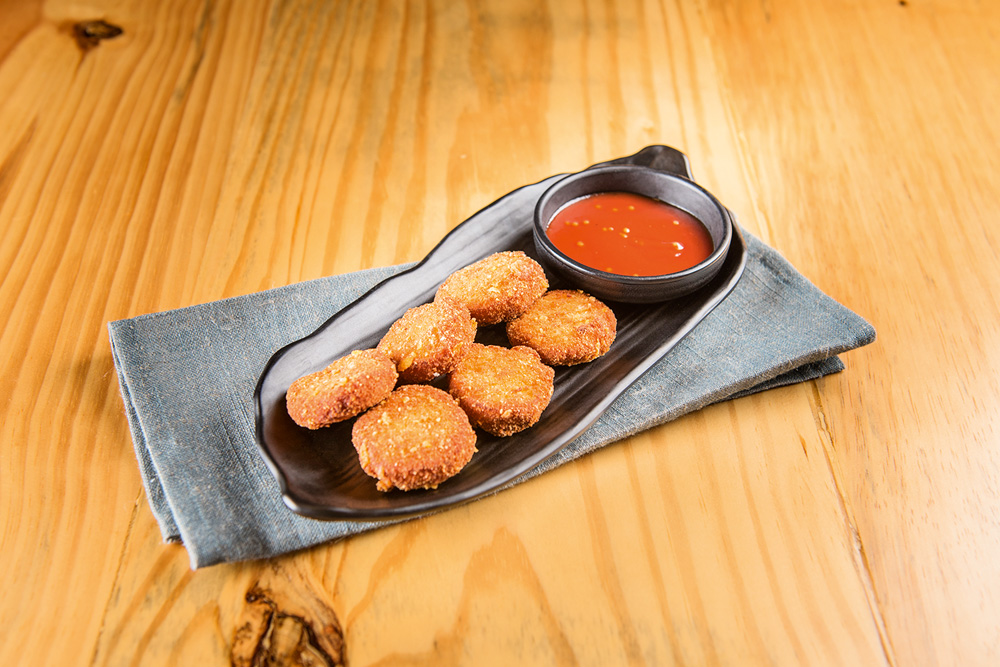 Porção de seis unidades de nuggets servidas junto de molho barbecue