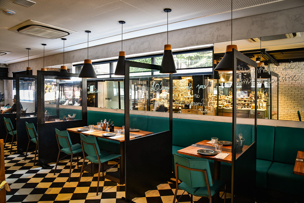Chez Claude Ambiente do restaurante decorado por cadeiras de estofado azulado e piso de mármore branco e preto