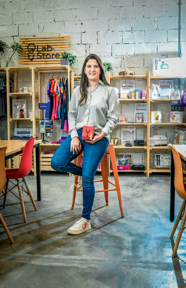 São Paulo 03 dezembro 2021FEMTECHS Foto Alexandre Battibugli VSP Imagem mostra mulher de calça jeans e camisa cinza com estantes de madeira atrás.