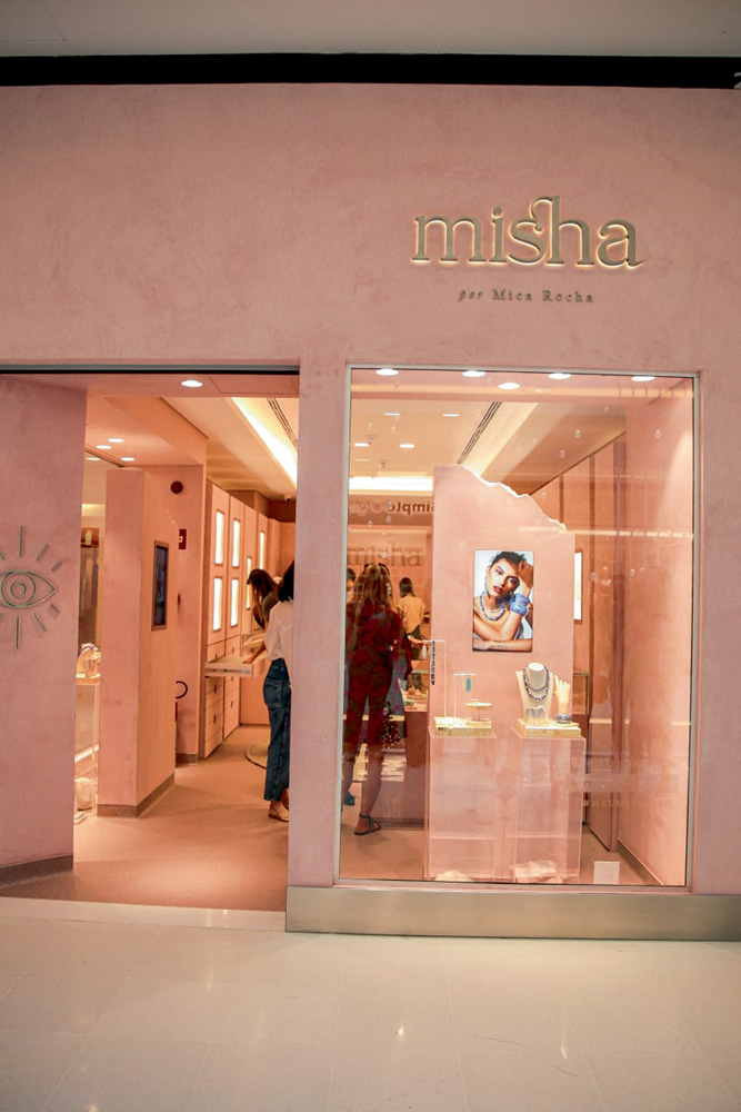 Misha 3_3.jpg Foto mostra fachada de loja. Dá para ver algumas prateleiras e pessoas dentro dela, assim como banner