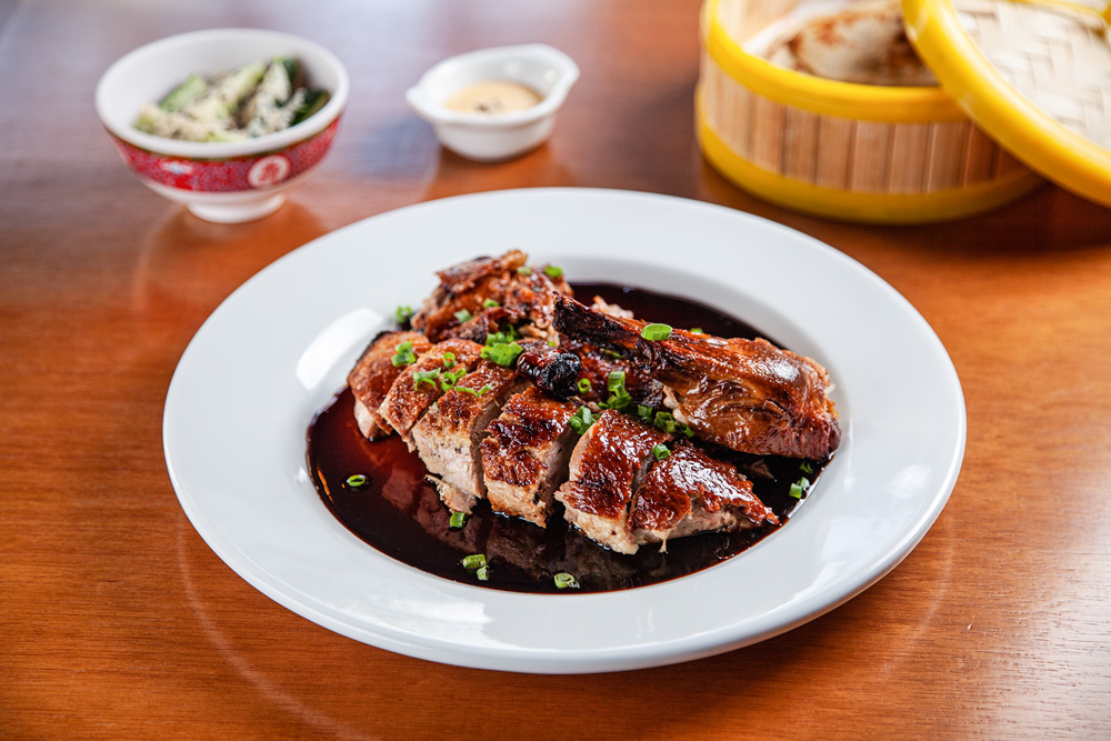 Cantón Peruvian & Chinese Food Pedaço de carne servida junto de molho shoyu em um prato fundo de cor branca