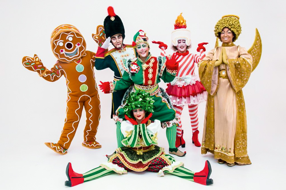 Cortejo de Natal na ZN Seis pessoas vestidas de personagens de Natal (biscoito, anjinho, árvore etc) posam em um fundo branco