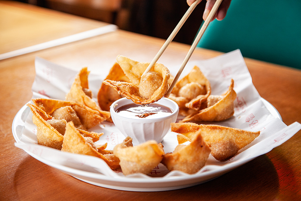Porção de wonton servida junto de molho de cor avermelhada