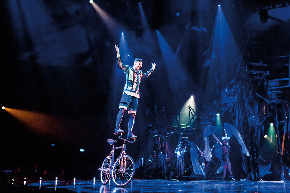 Foto de um acrobata do Cirque du Soleil se equilibrando em cima de uma bicicleta.
