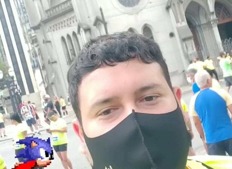 Selfie tirada por Diego. Ele é um homem branco de cabelos escuros, usa uma máscara preta e uma blusa amarela. No registro, ele se preparava para o início da prova de corrida.