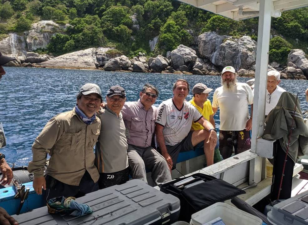 A foto mostra o presidente Bolsonaro em uma embarcação no mar ao lado de outras pessoas