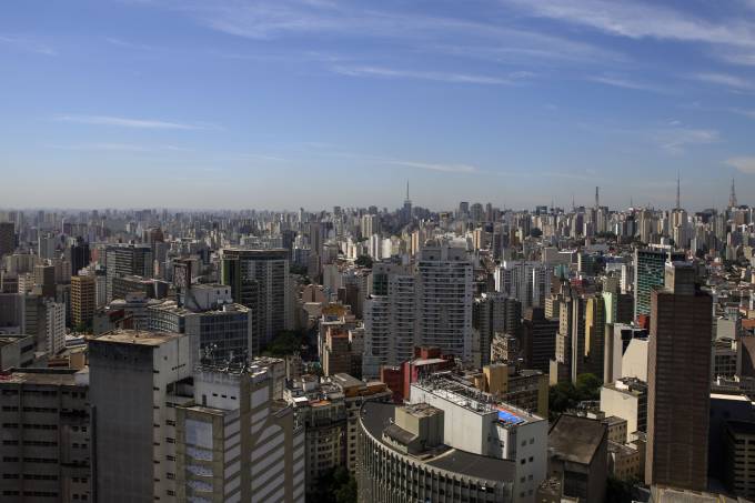 Imagem mostra horizonte de prédios sob céu azul sem nuvens