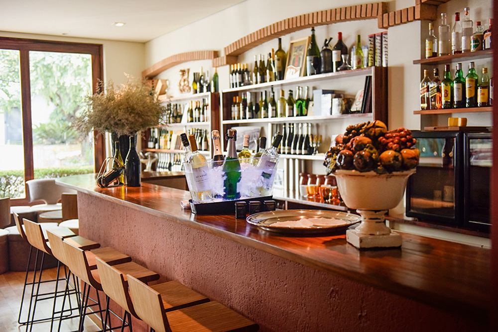 Ambiente de restaurante com balcão e garrafas expostas em prateleiras