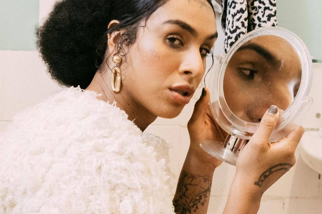Imagem de Lina com um espelho redondo nas mãos