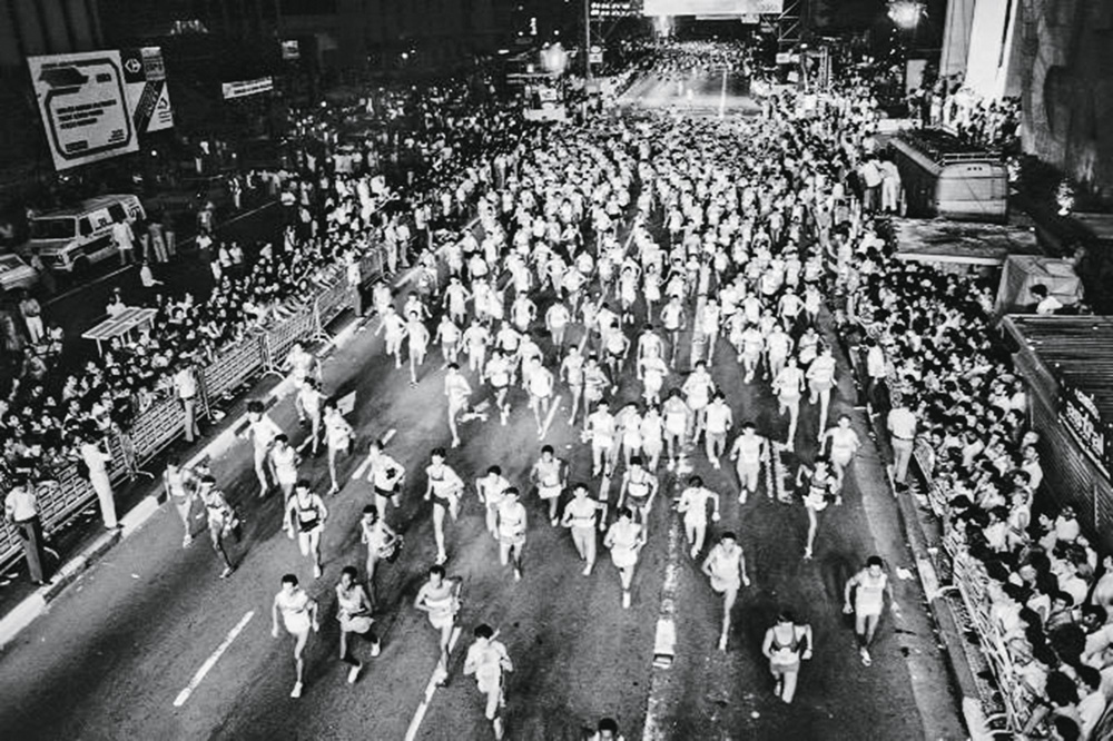 Vista-aérea-da-Corrida-de-São-Silvestre-na-Avenida-Paulista_JORGE ROSENBERG_divulgação.jpg (1) Imagem mostra multidão de pessoas correndo em avenida.