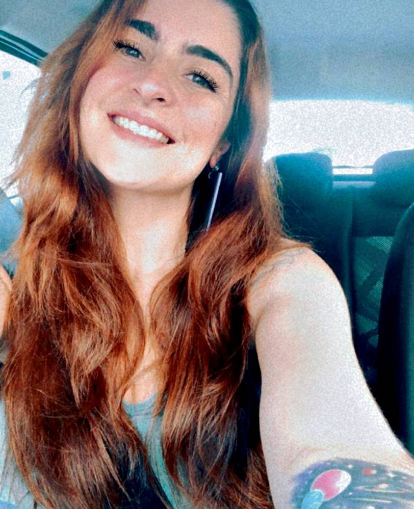 WhatsApp Image 2022-01-21 at 15.36.56.jpeg Imagem mostra mulher de cabelo ruivo dentro de carro, sorrindo para a câmera.