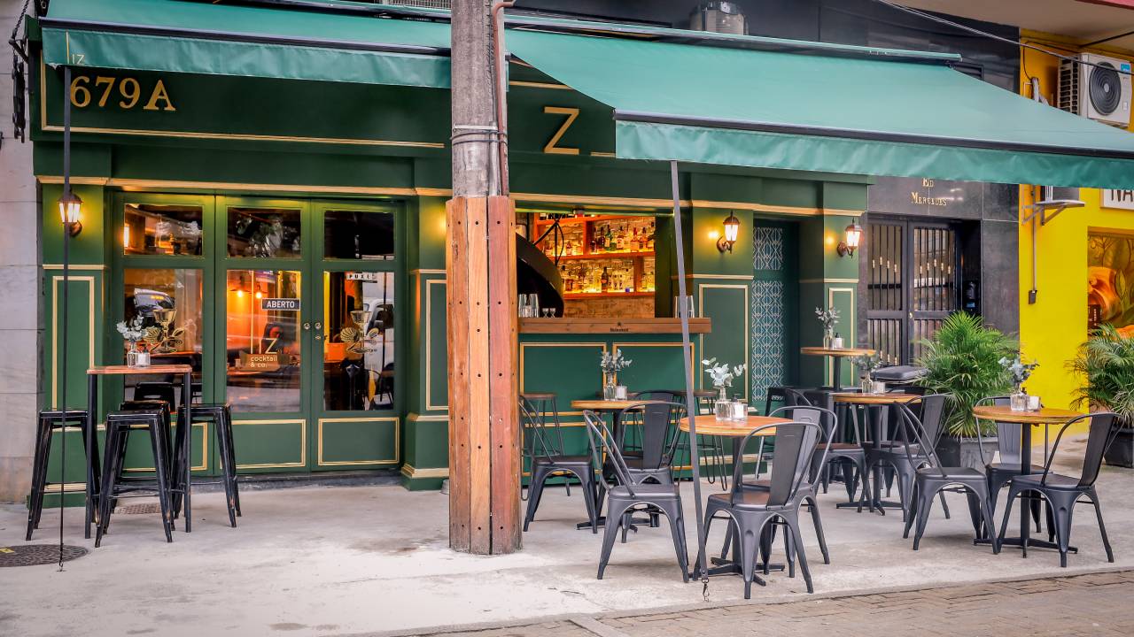 Fachada de bar verde com mesas em frente