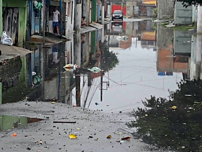 córrego Itaim Imagem mostra rua completamente alagada. Um carro pode ser visto ao fundo, do outro lado do corpo d'água que tomou conta do asfalto.