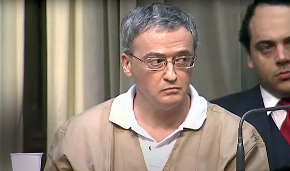 Imagem mostra homem de óculos e cabelo grisalho vestindo camisa branca com colete bege.