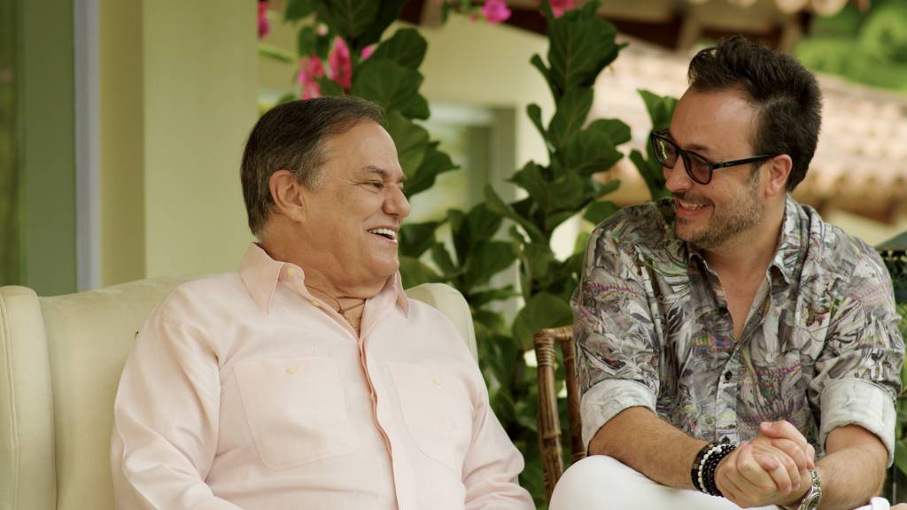 Rodrigo Righetti e Ronnie Von (DIVULGAÇÃO) (2) Ronnie Von e Rodrigo Righetti sentados lado a lado. Ronnie veste camisa rosada e Rodrigo uma camisa estampada.