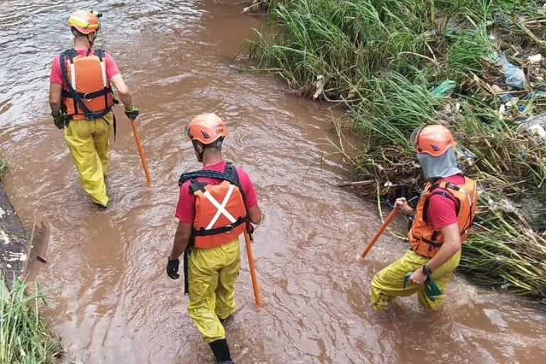 Imagens mostram três homens do Corpo de Bombeiros trabalhando dentro de um córrego