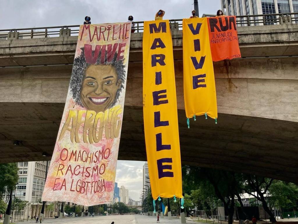 A foto mostra faixs estendidas no cenro de SP que lembram o assassinato de Marielle Franco e de Anderson Gomes