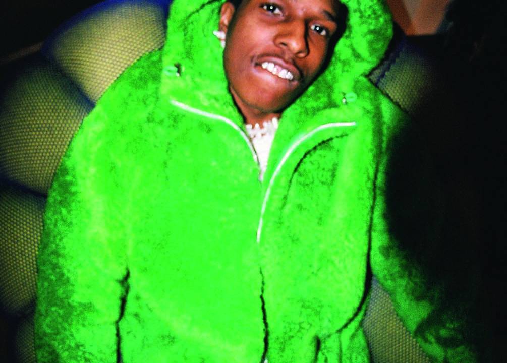 Imagem mostra homem de casaco verde e calça jeans sentado em escada.
