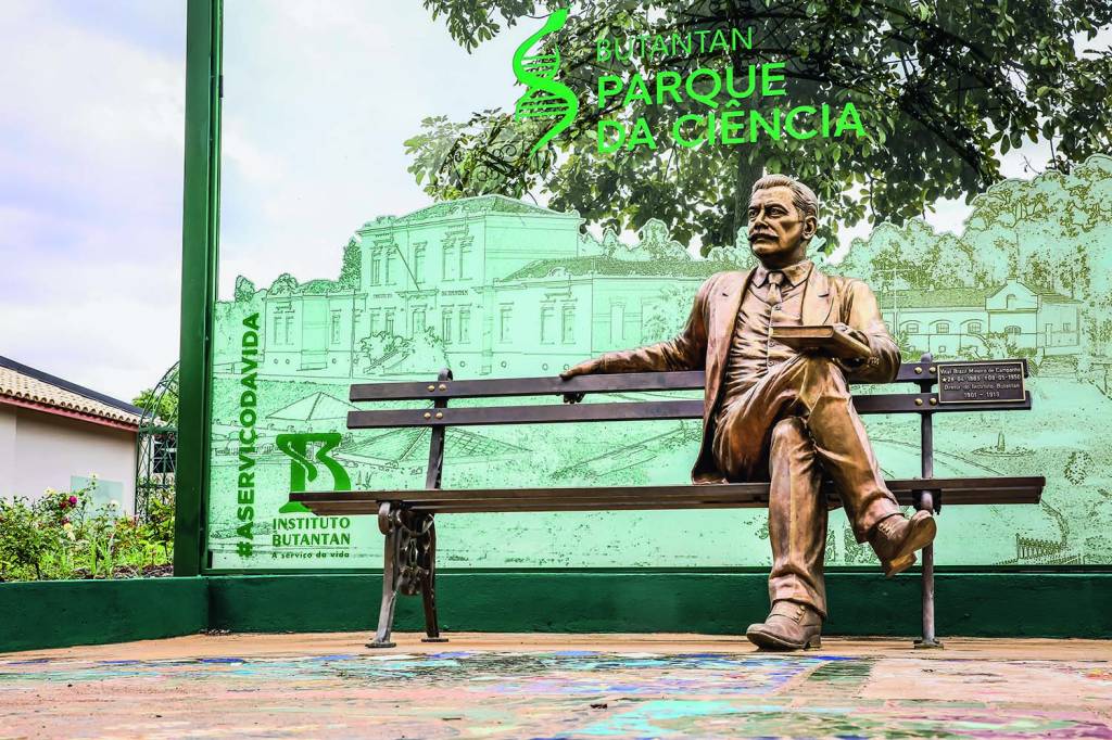 Imagem mostra banco com estátua de bronze de homem sentado, segurando um livro.