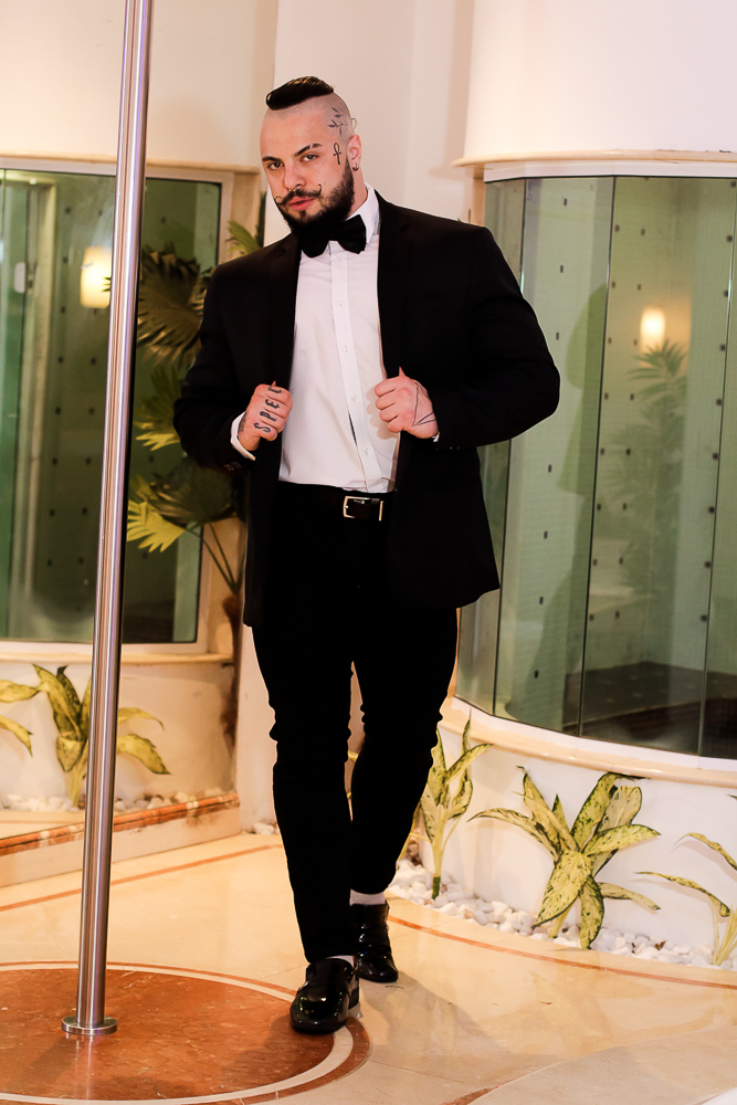 Gabriel Spec (Francis Lima-Divulgação) (1) Gabriel Spec posa com blazer preto. Ele tem tatuagens no rosto, um moicano e bigode curvado.