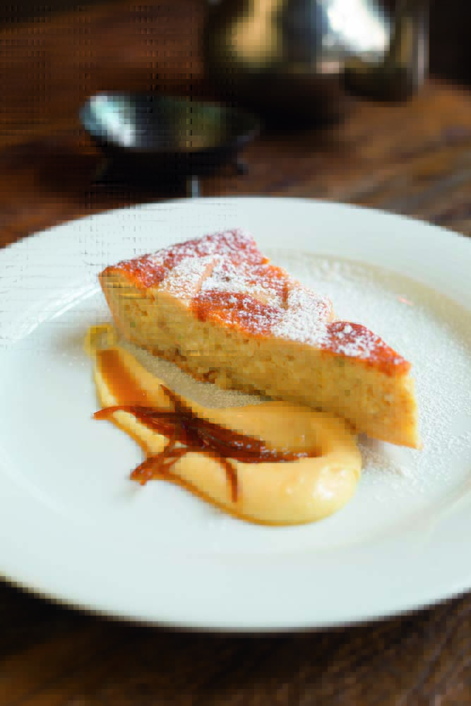 Vinarium Antica Trattoria Fatia de torta servida sobre pequeno prato raso de louça branca e junto de creme de cor levemente amarelada