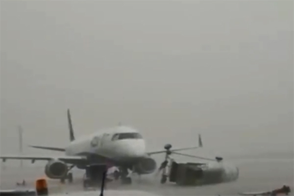 Imagem mostra escada caída ao lado de avião parado no aeroporto de Guarulhos, com muita chuva