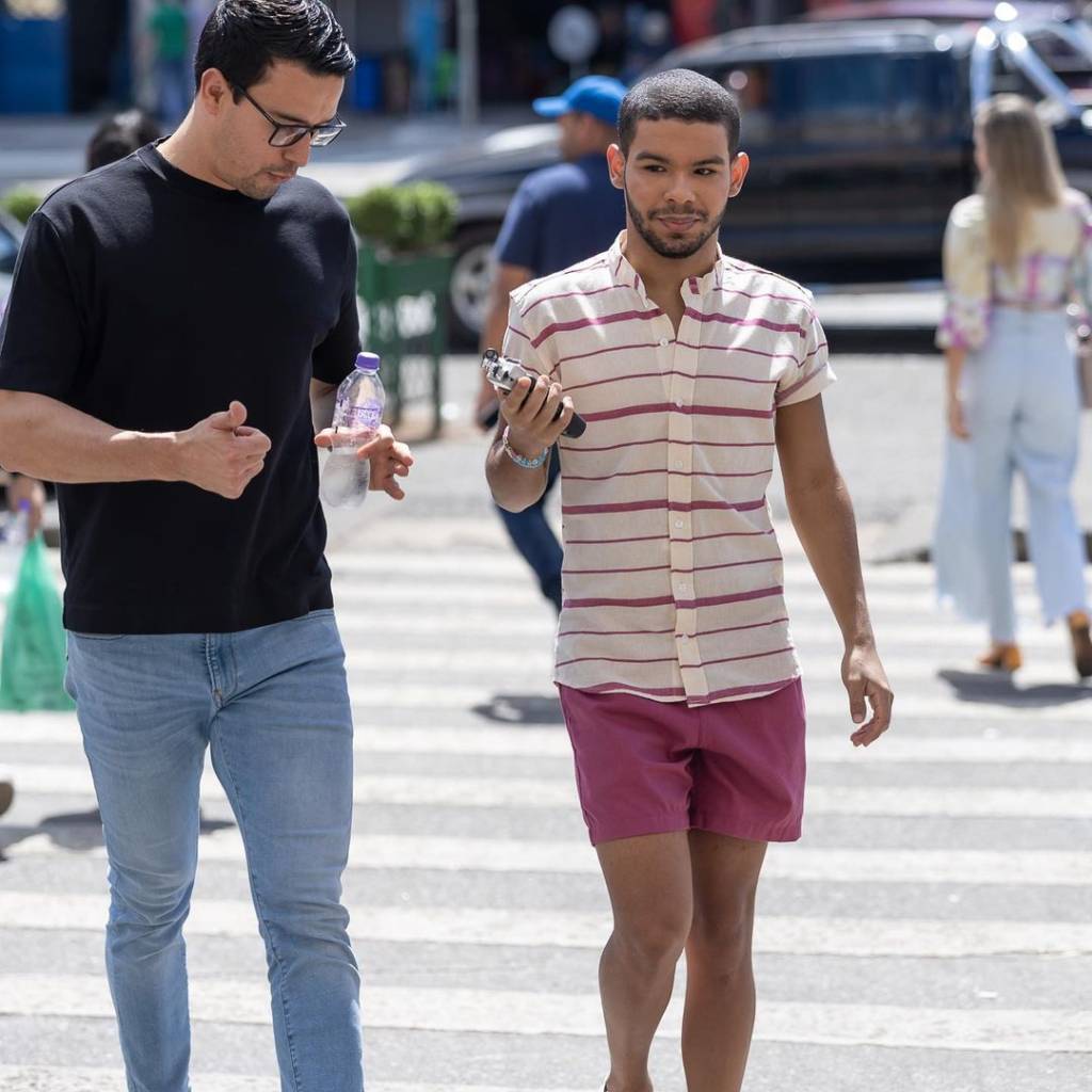 Thiago Salvático (à esq.), de camiseta preta e calça jeans, Vyni (à dir.) de camisa listrada, short linho