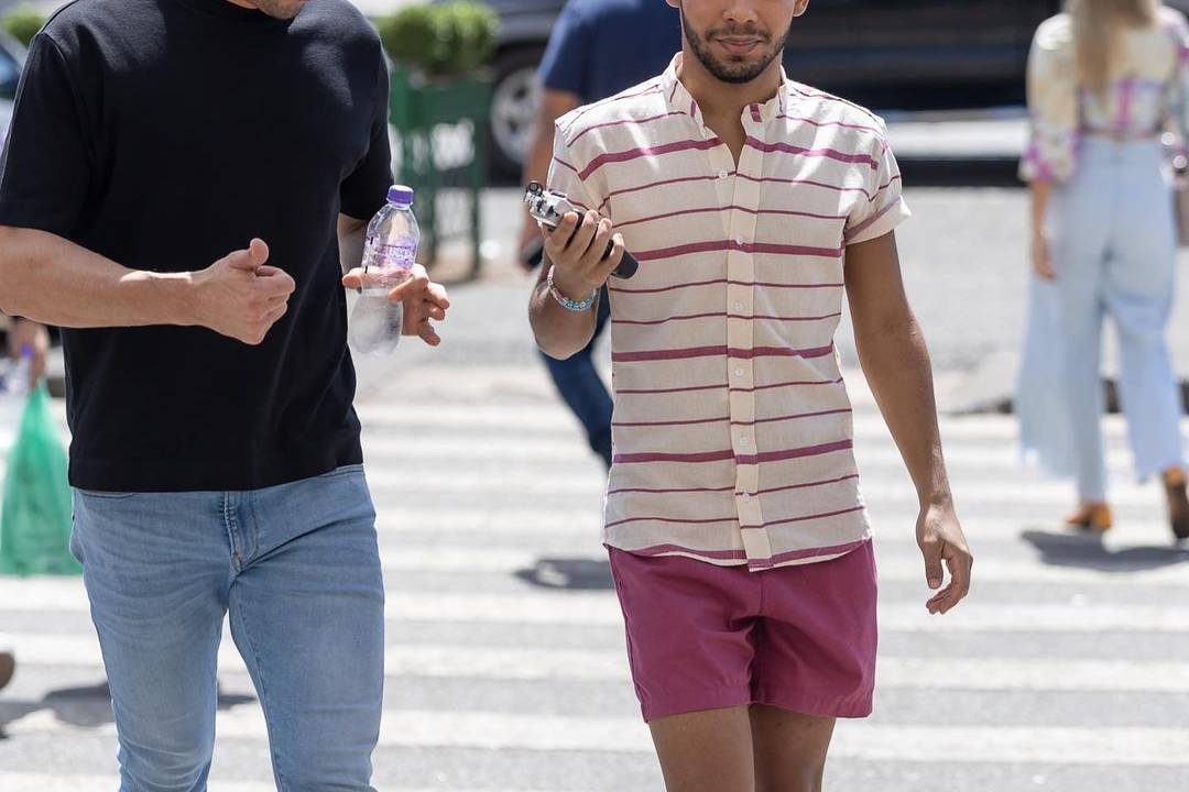 Thiago Salvático (à esq.), de camiseta preta e calça jeans, Vyni (à dir.) de camisa listrada, short linho