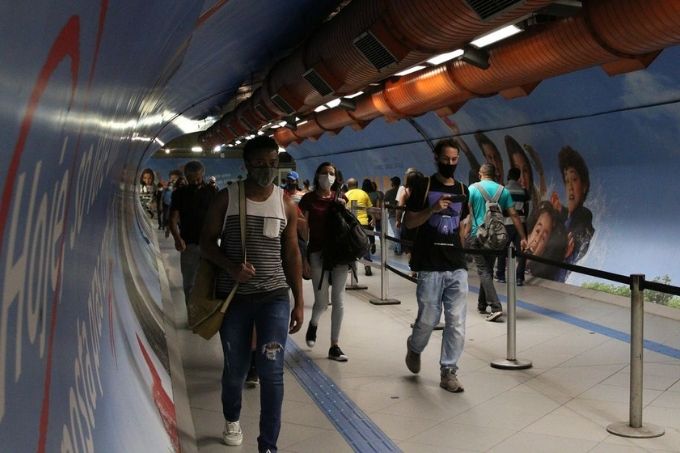 Pessoas caminhando em túnel de transição de estações no metrô