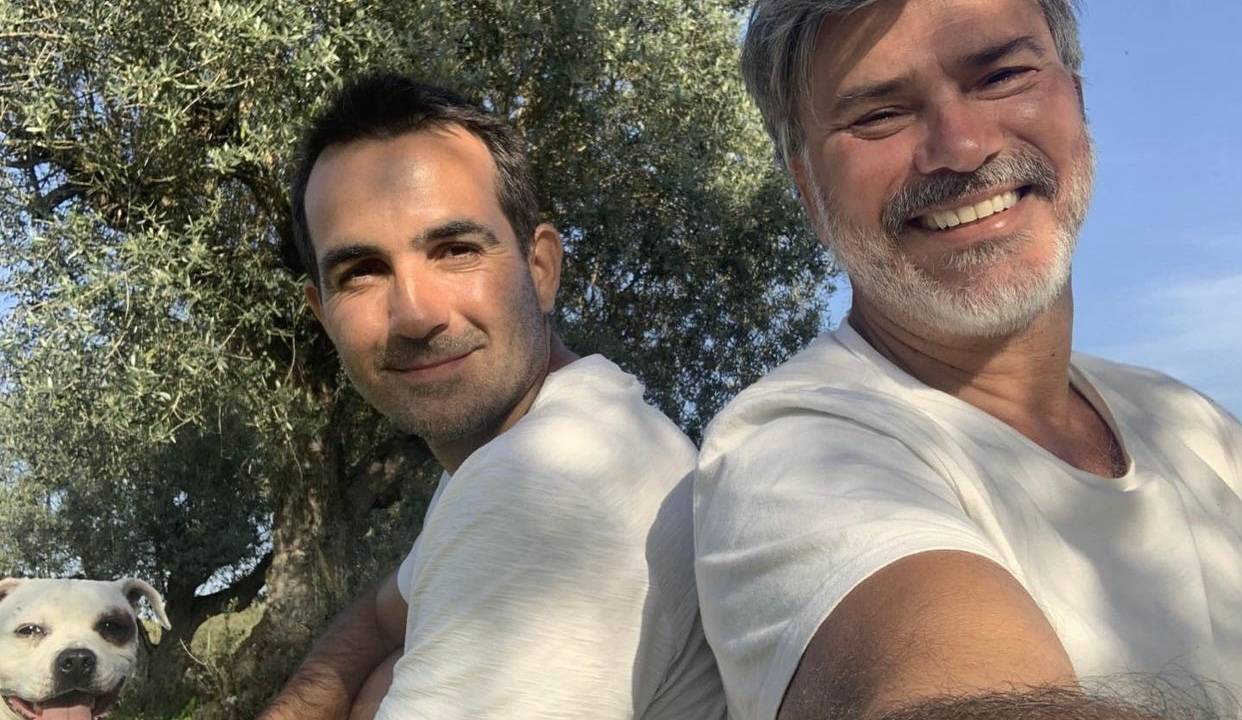 Imagem mostra dois homens de camisetas brancas, sorrindo