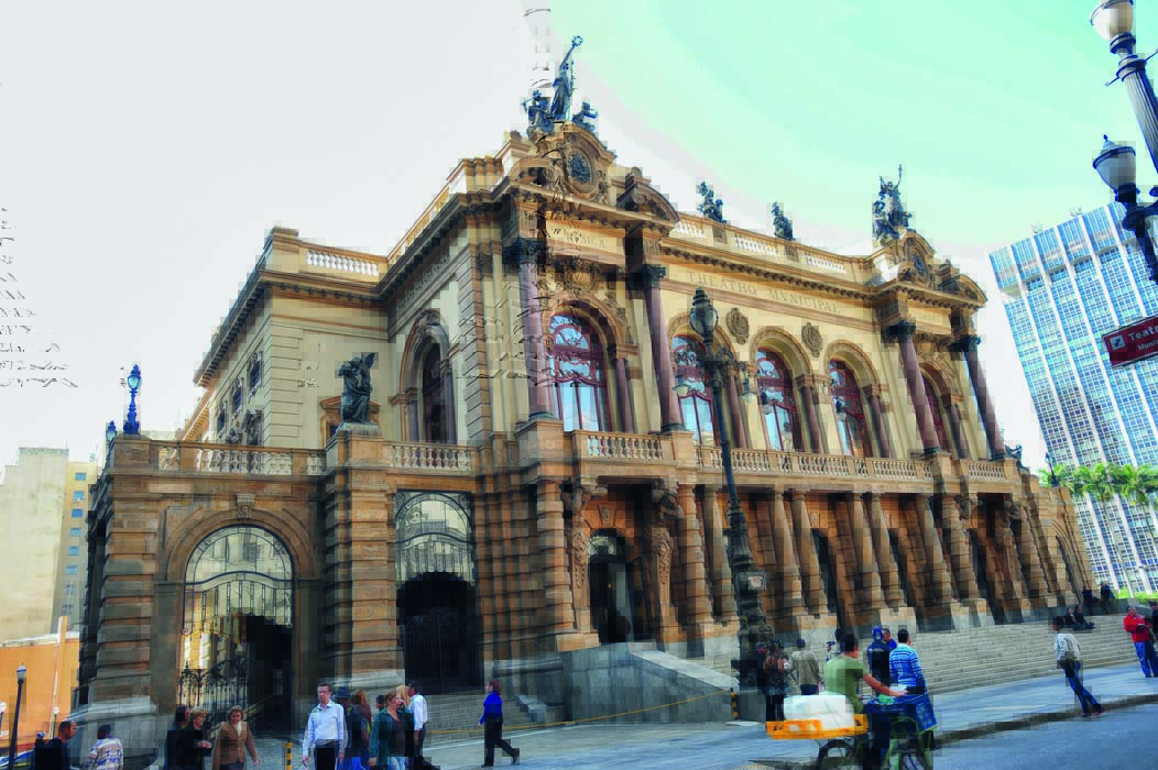 Teatro Municipal em São Paulo visto em sua extensão. Pessoas andam na rua que está na frente