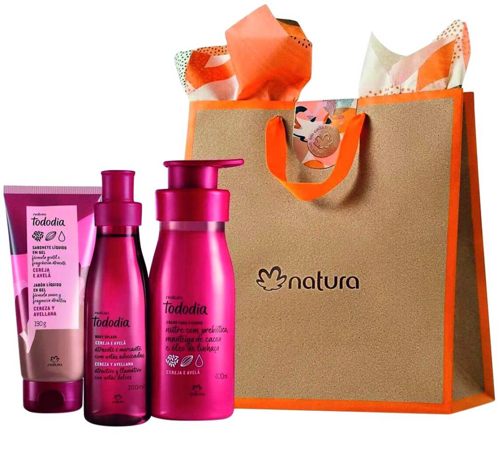 kit natura Kit de cremes da Natura. Três frascos de formatos diferentes, todos na cor rosa pink, ao lado de uma sacola de papelão com detalhes em laranja e o nome da marca no centro