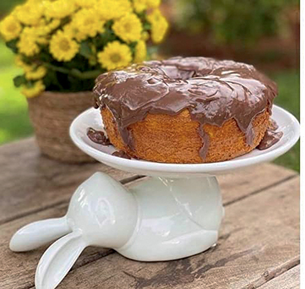 Boleira branca de coelho com um bolo em cima