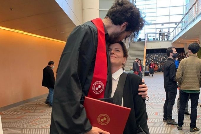 Debora Bloch na formatura de seu filho, que aparece de beca lhe dando um beijo na cabeça