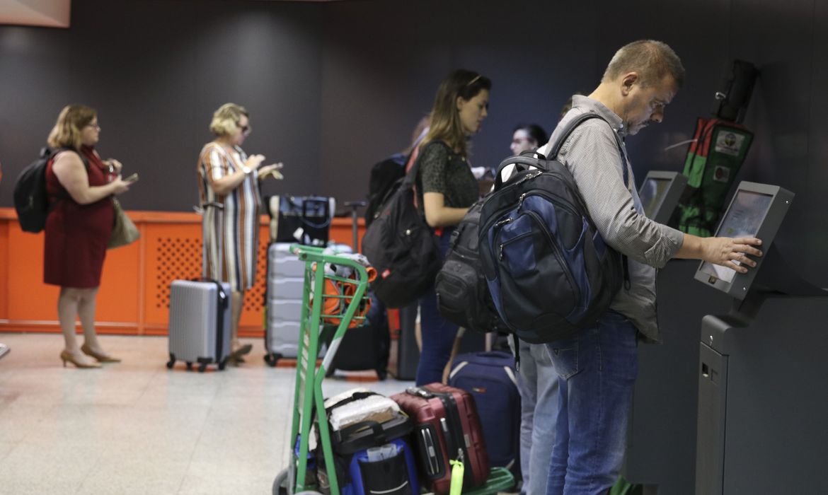 Passageiros usando máquina de autoatendimento para despachar bagagens