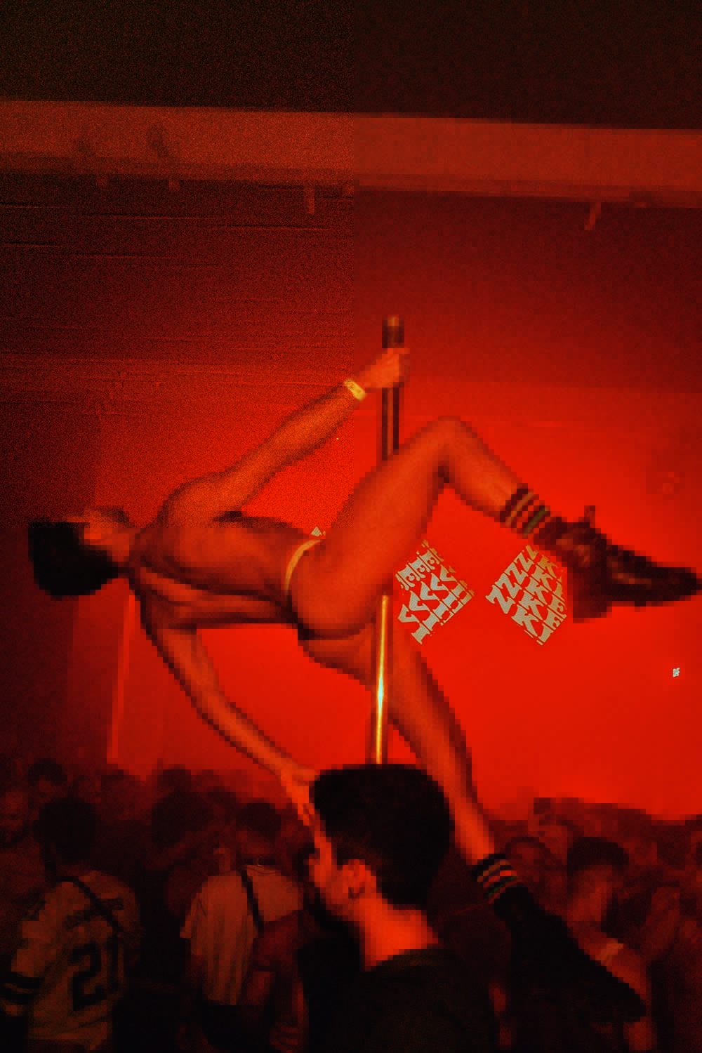 5 — (PÁGINA 4) ZIGSTUDIO (Fred Othero-Divulgação).png Imagem mostra pessoa pendurada em pole dance em ambiente iluminado por luz vermelha