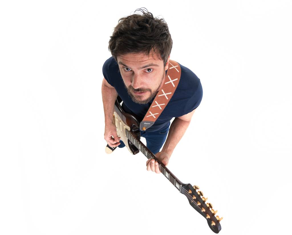 Sérgio Guizé (Lucas Marasta) Foto do alto, com Sérgio Guizé visto de cima segurando uma guitarra.