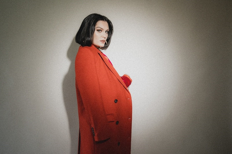 Imagem mostra mulher de paletó vermelho, de perfil, em frente a parede branca