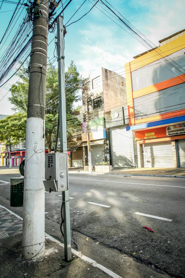 Imagem mostra dois postes em uma rua sem movimento no Brás