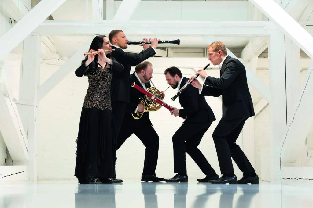 Carion. Foto_ J¿nis Porietis.jpg Imagem mostra cinco pessoas com roupas de gala tocando instrumentos de sopro, em pé.