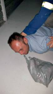 imagem mostra homem com o rosto no chão e uma sacola ao lado