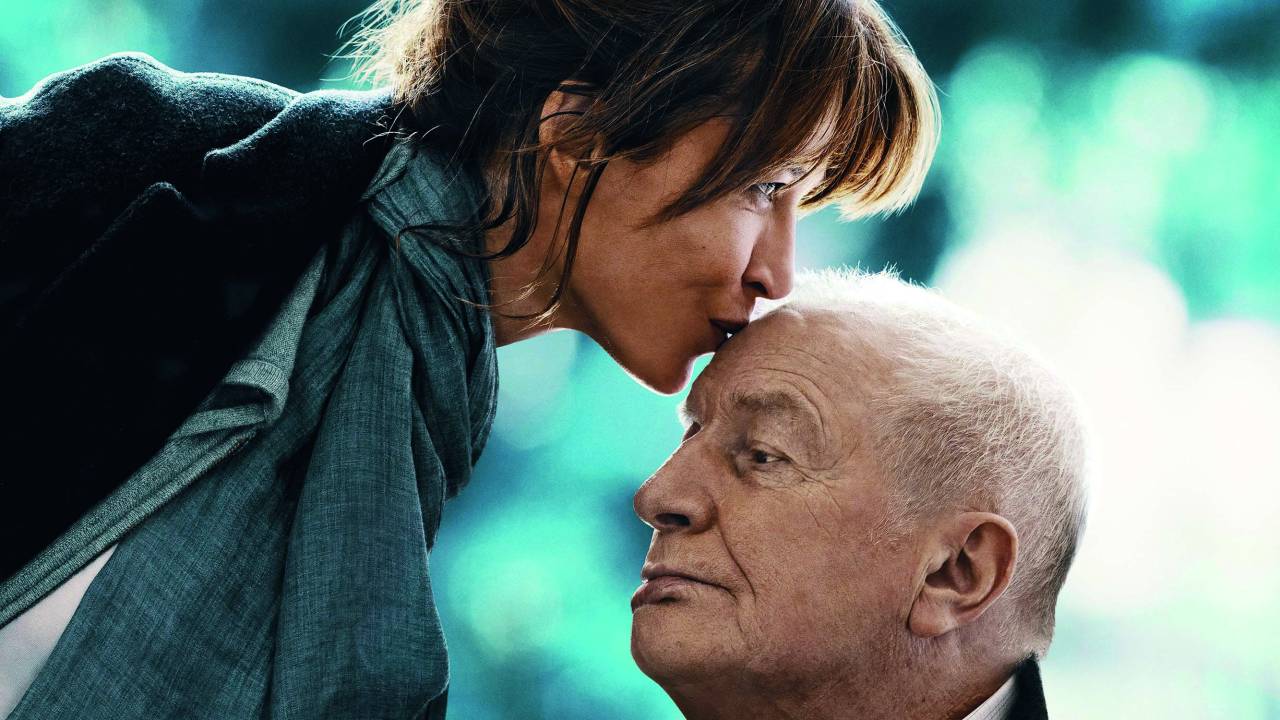 Imagem mostra mulher beijando testa de homem idoso