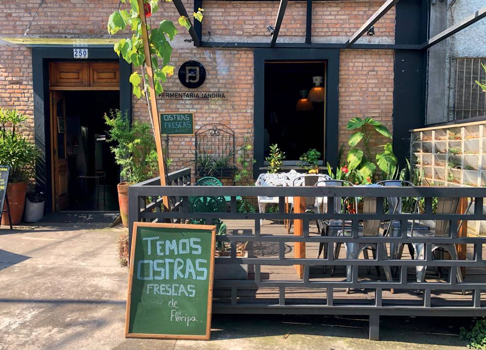 Fachada de bar com varanda e parede de tijolos expostos