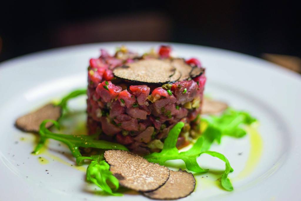 Steak tartare, com filé-mignon em cubos temperados com azeite, sal, pimenta-do-reino, alcachofra, alcaparra, cebola picada, toque de alho, suco de limão-siciliano e pasta de trufas.