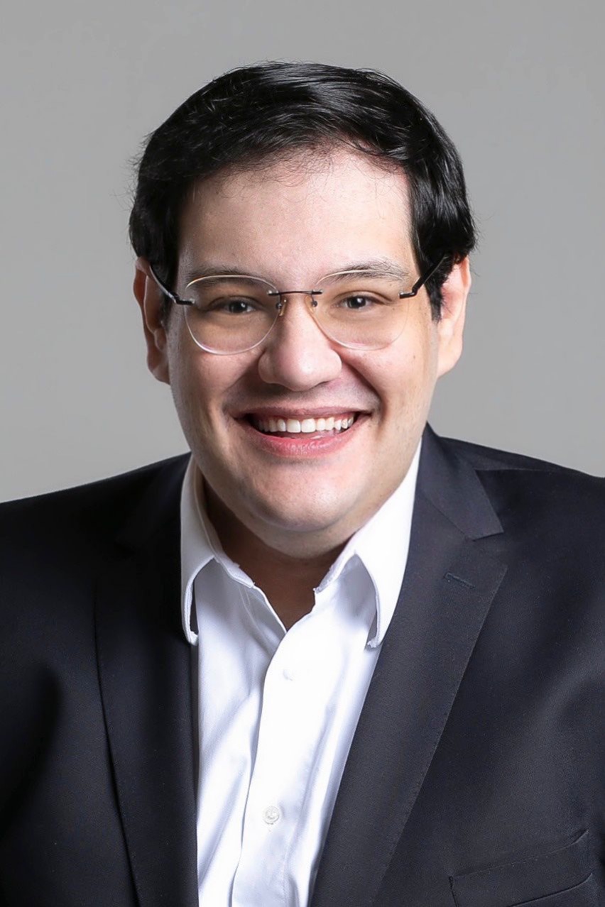 Alberto Haddad (kikafotografa -Divulgação) Alberto Haddad sorri para a câmera. Veste blazer preto, óculos de grau e camisa branca.