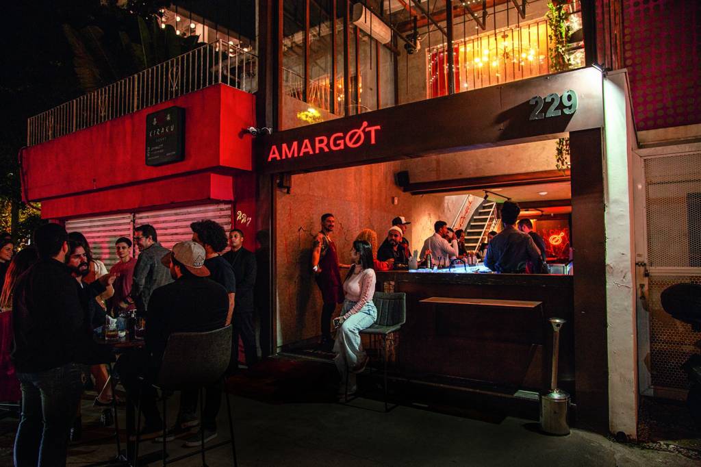 Fachada de bar com pessoas sentadas e em pé conversando.