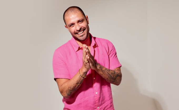 Imagem mostra homem careca de camisa rosa sorrindo