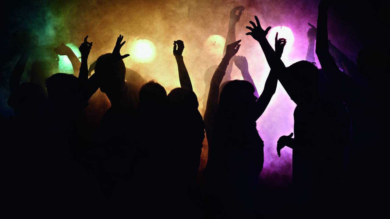 Silhuetas escuras em pista de dança.