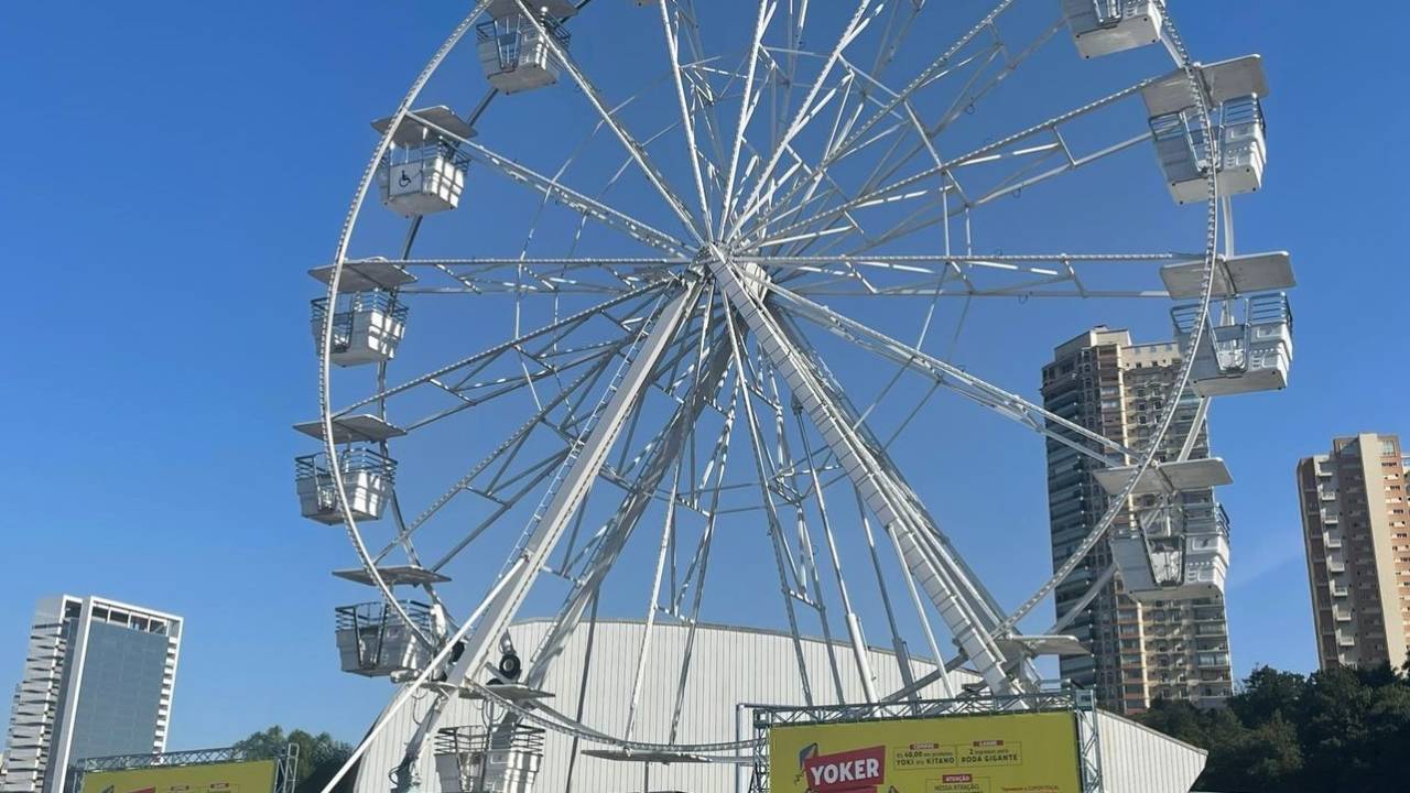 Foto exibe roda-gigante em céu azul.